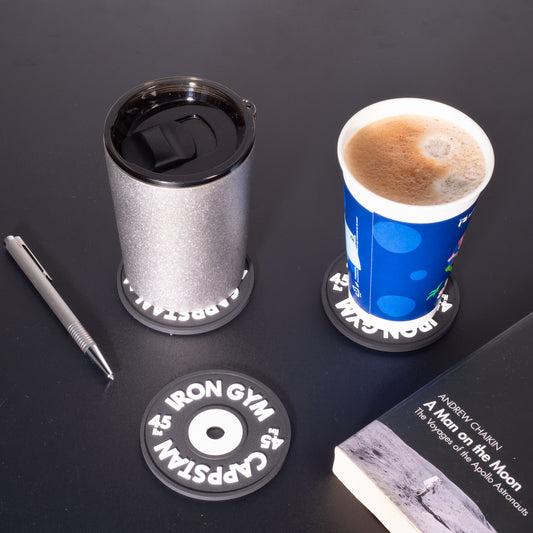 This product photography lifestyle image shows black coasters with cups and a book.